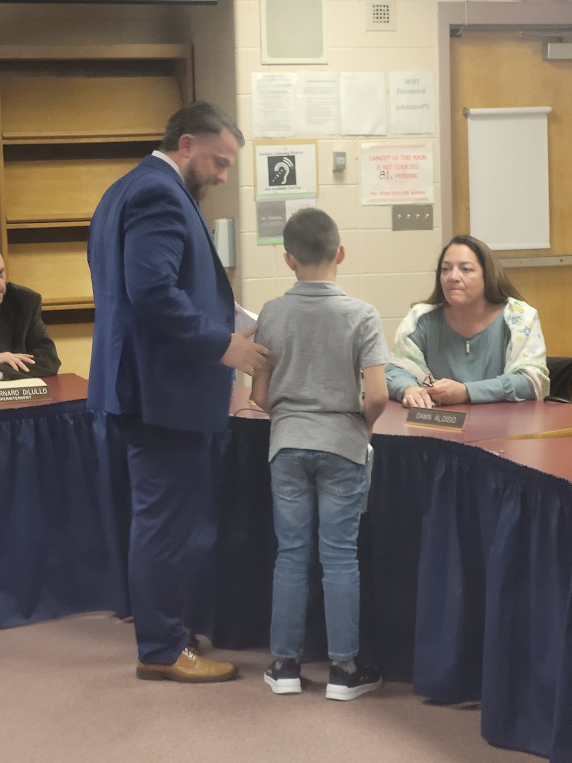 HUGS ALL AROUND: Matt Velino, the now former assistant principal at Johnston Senior High School has been promoted to the school’s top administrator post — the Principal. He introduced his son to some of the School Committee members after they approved his hiring.